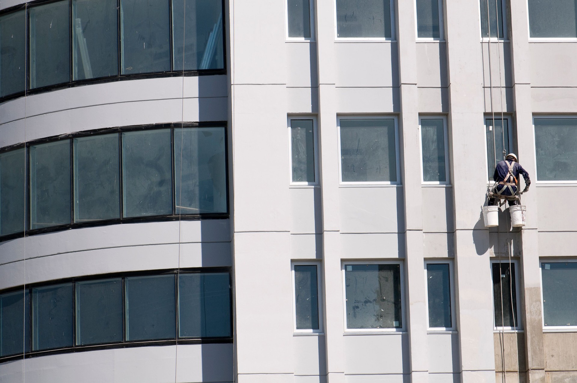 A worker hanging on ropes on the outside of a new building