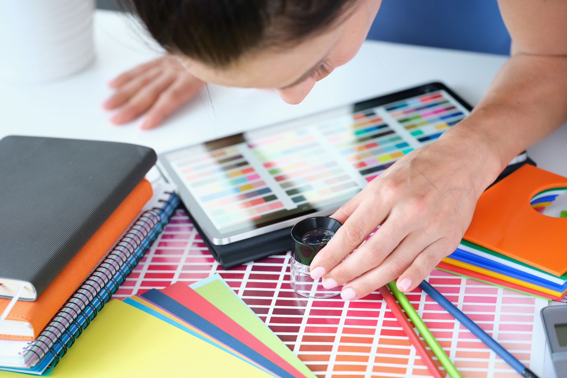 Woman designer looks through magnifying glass at color palette with different shades of colors