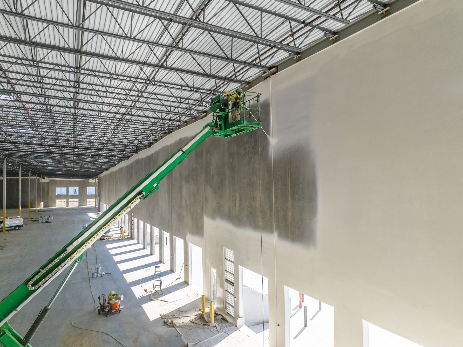 Worker on cherry picker painting wall